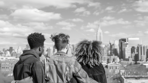 A black & white photo of people looking at the NYC skyline.